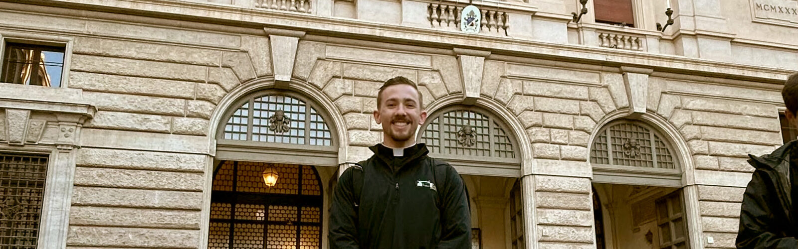 Photo of Ryan Pierce in front of the Pontifical North American College, specifically Gregorian University in Rome.